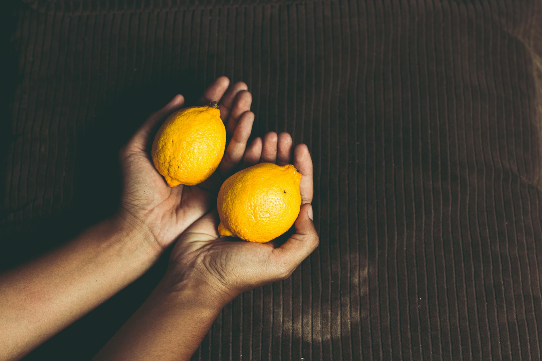Two fresh lemons held in cupped hands, symbolizing care and renewal