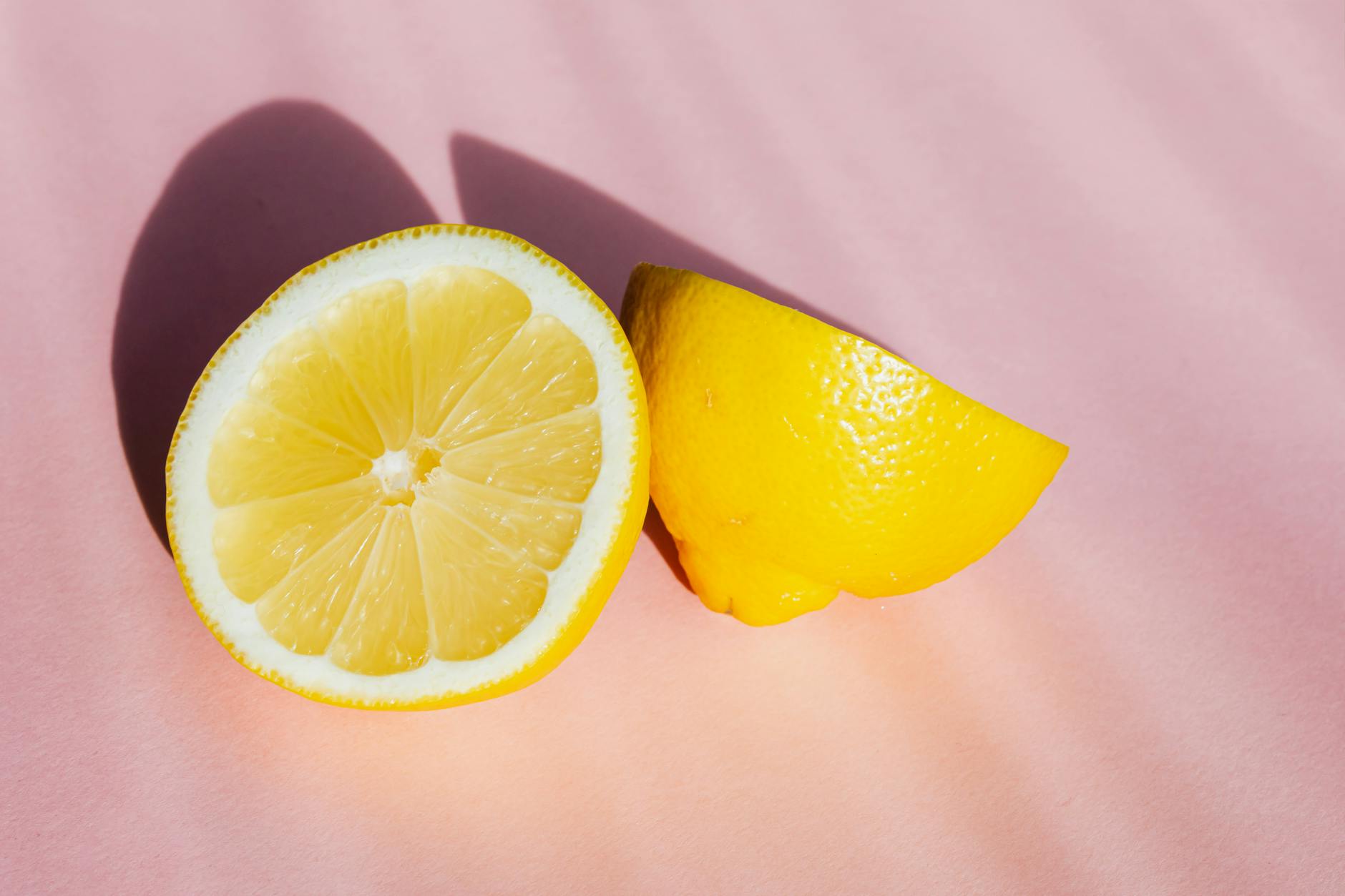 Fresh lemon halves on a pink background in natural light