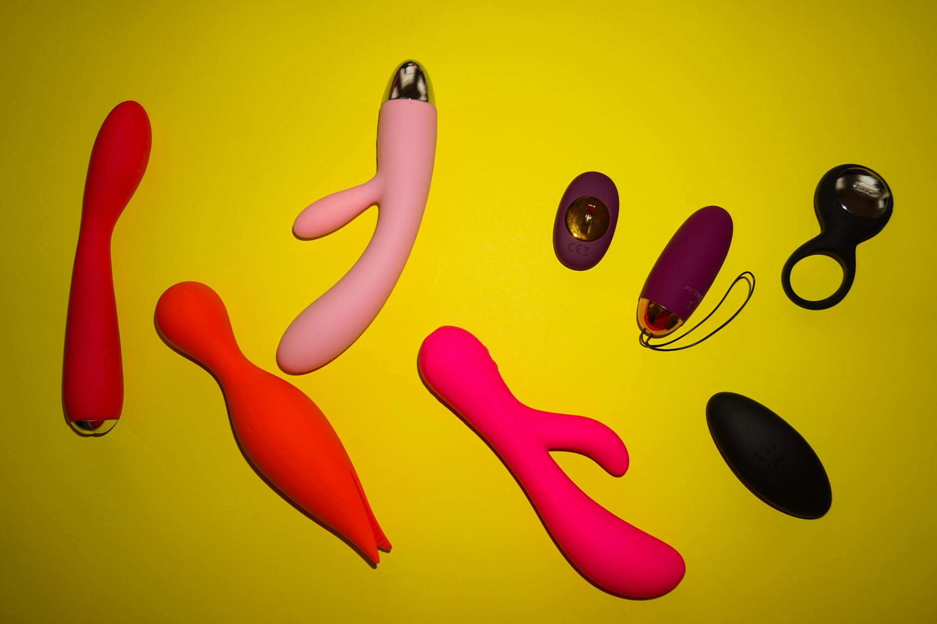 Vibrant collection of clitoral vibrators arranged on a bright yellow surface, showcasing diverse designs