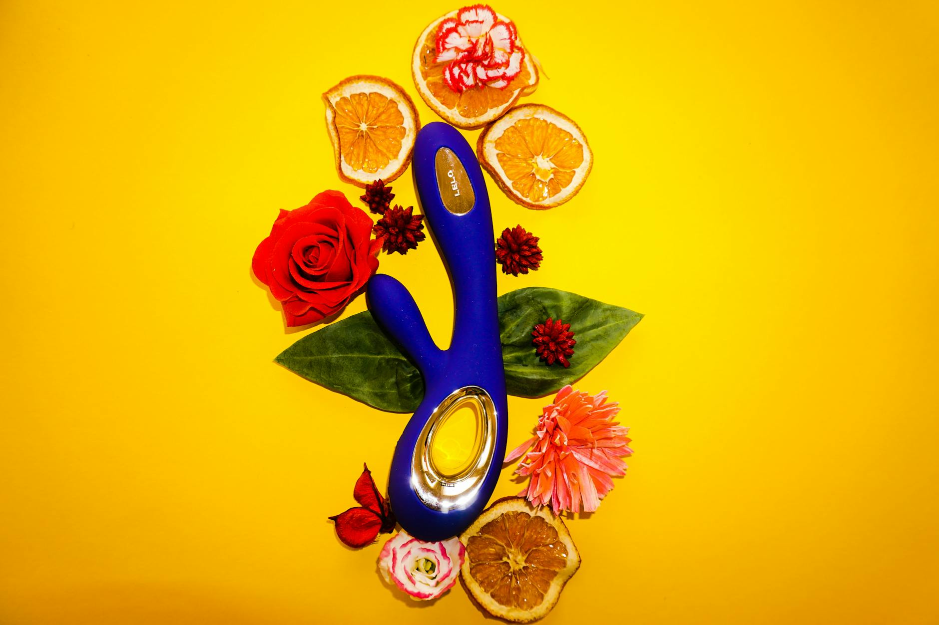 Blue lemon vibrator surrounded by fresh lemons and flowers on a bright yellow background
